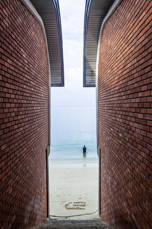 Malaysian woman takes a swim on Pangkor Island, captured between brick wallsの写真素材