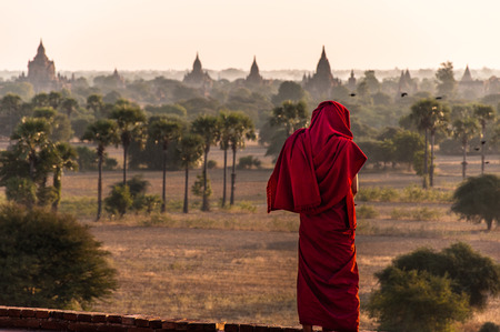 A burmese monk looks over the pagdodas of Bagan, Pyathada Temple in Bagan, Myanmarの写真素材