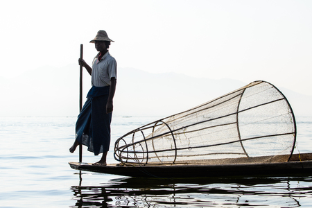 INLE LAKE, MYANMAR - FEBRUARY 15, 2014: Burmese fisherman on bamboo boat catching fish in traditional way with handmade net. Inle lake, Myanmar (Burma) travel destinationのeditorial素材