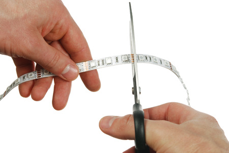 The man cut the LED stripe with scissors on a white backgroundの写真素材