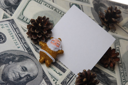 Santa with a Christmas tree cone and card on the background of hundred dollar billsの写真素材