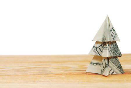 Christmas tree made of hundred dollar bills on a wooden board on a white backgroundの写真素材
