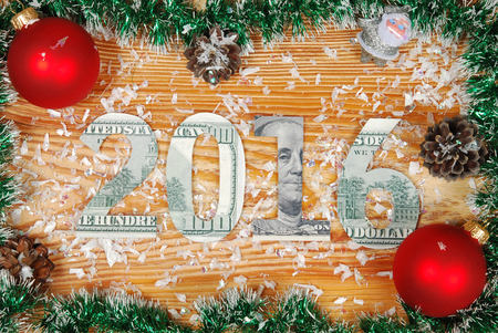 the inscription 2016 carved out $ 100 bills on a wooden board