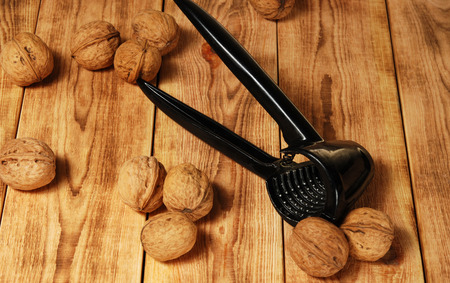 Walnuts on the wooden background with the tool for chopping