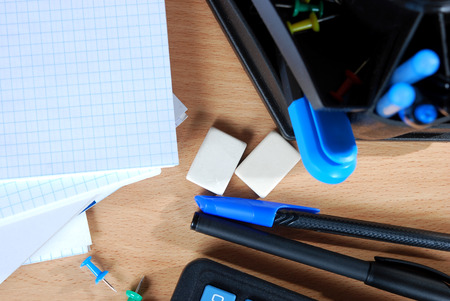 opened notebook with blue text marker, erasers and calculator on the table
