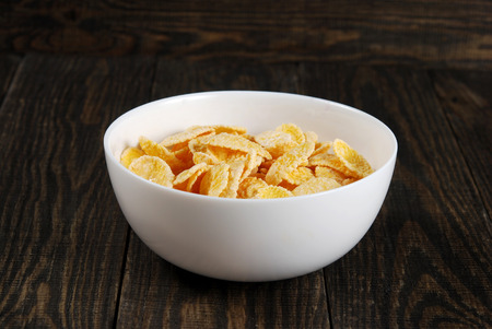Corn flakes in small white bowls on a dark wooden backgroundの写真素材