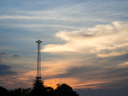 Silhouette spotlight pole like UFO with sunset and cloudy backgroundの写真素材