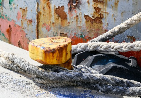 Bollard on the pier of the harbor of Agia Galini in Crete. A thick rope is tied around it to moor a...