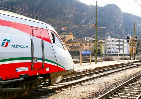 Tracks and a platform of the Bolzano railroad station in South Tyrol with a locomotive of a train.
