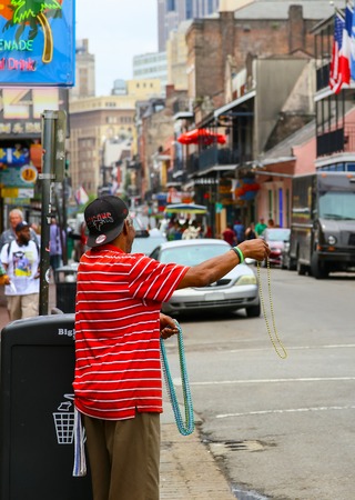 New Orleans, USA - May 14, 2015: Street vendor advertising colorful Mardi Gras beads on busy Bourbon Street in French Quarter.のeditorial素材