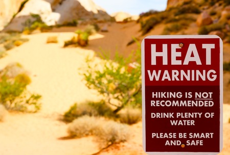Valley of Fire, USA - June 4, 2015: Sign with a Heat Warning. It stands at the White Domes in the Valley of Fire. Hiking is not recommended. In the background are sand, bushes and rocks.の写真素材