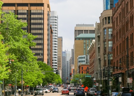 Denver, USA - May 25, 2016: Part of the lower downtown district called LoDo with office buildings and restaurants, cars are driving on the street with roadwork ahead, few people are walking by.のeditorial素材