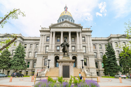 Denver, USA - May 25, 2016: Front view of the Colorado State Capitol including the gold dome with the Civil War Monument in front. Three women are walking by.のeditorial素材