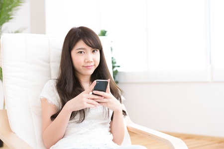The Young woman who uses the smartphone in a roomの写真素材