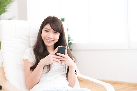 The Young woman who uses the smartphone in a roomの写真素材