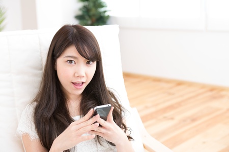 The Young woman who uses the smartphone in a roomの写真素材