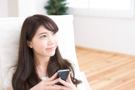 The Young woman who uses the smartphone in a roomの写真素材