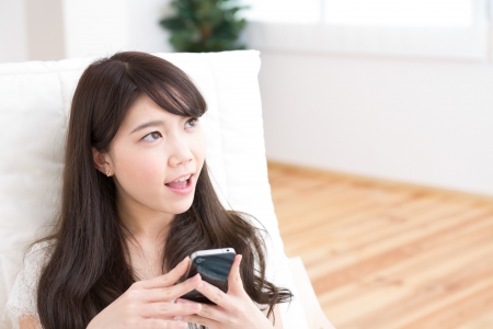 The Young woman who uses the smartphone in a roomの写真素材