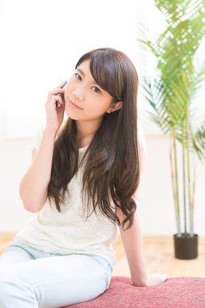 The Young woman who talks on the telephone in a roomの写真素材