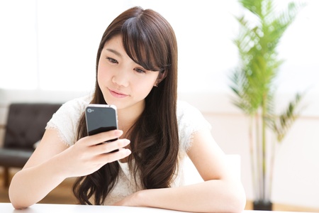 The Young woman who uses the smartphone in a roomの写真素材