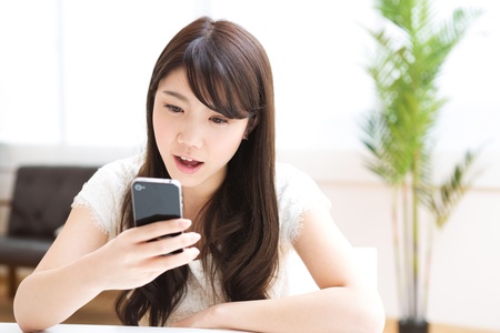 The Young woman who uses the smartphone in a roomの写真素材