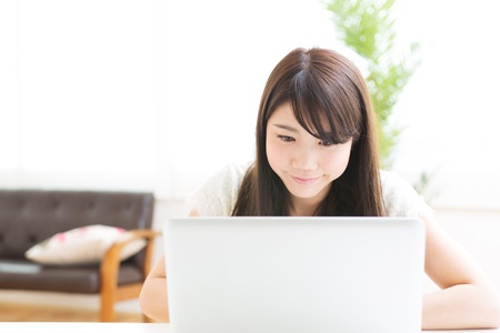 The Young woman who uses the computer in a roomの写真素材