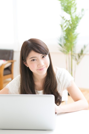 The Young woman who uses the computer in a roomの写真素材