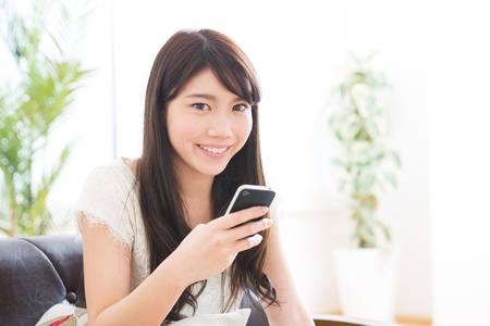 The Young woman who uses the smartphone in a roomの写真素材