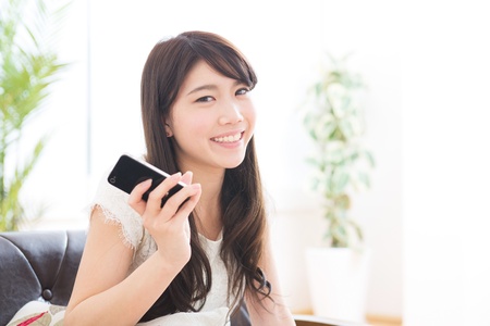 The Young woman who uses the smartphone in a roomの写真素材
