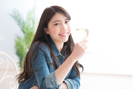 The young woman who drinks wine in a roomの写真素材