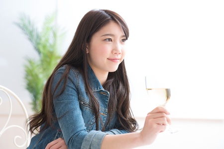 The young woman who drinks wine in a roomの写真素材