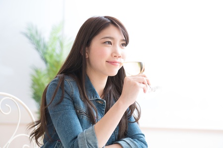 The young woman who drinks wine in a roomの写真素材