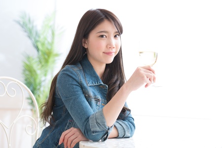 The young woman who drinks wine in a roomの写真素材