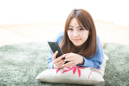 The Young woman who uses the smart phone in a roomの写真素材