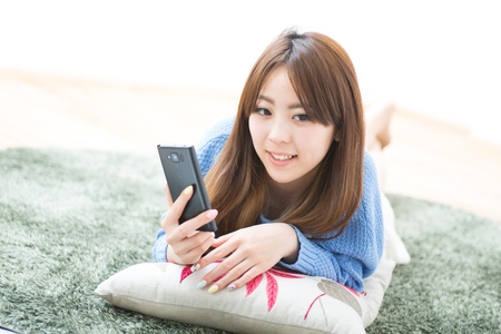 The Young woman who uses the smart phone in a roomの写真素材