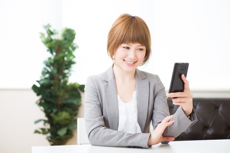 Beautiful young asian businesswoman to see a smart phoneの写真素材