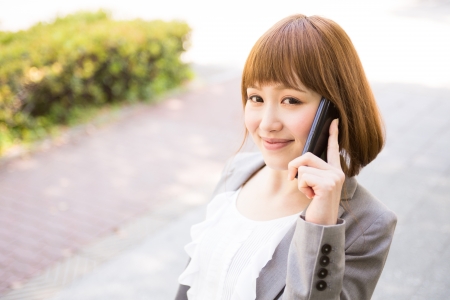 Beautiful young asian businesswoman who talks on the telephoneの写真素材