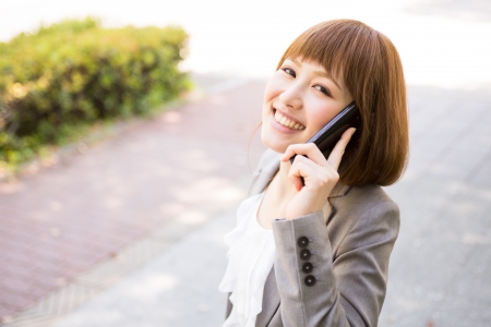 Beautiful young asian businesswoman who talks on the telephoneの写真素材