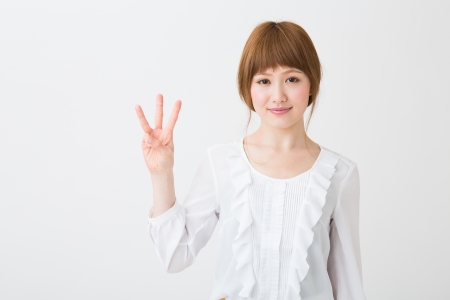 young attractive asian woman indicating the number threeの写真素材