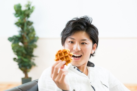 young asian man who eats a waffleの写真素材