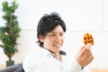 young asian man who eats a waffleの写真素材