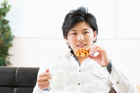 young asian man who eats a waffleの写真素材