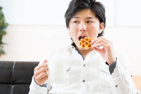 young asian man who eats a waffleの写真素材