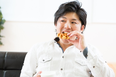 young asian man who eats a waffleの写真素材