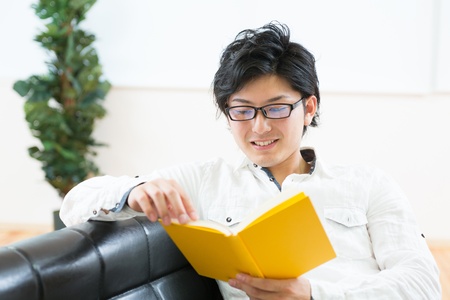 young attractive asian man who reads a bookの写真素材