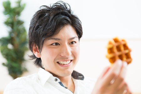young asian man who eats a waffleの写真素材
