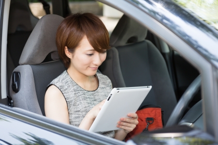 Beautiful young asian woman using tablet computer in a carの写真素材