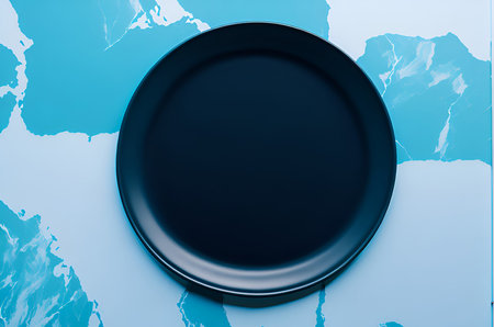 Empty black plate on blue map background. Top view. Copy space.の写真素材