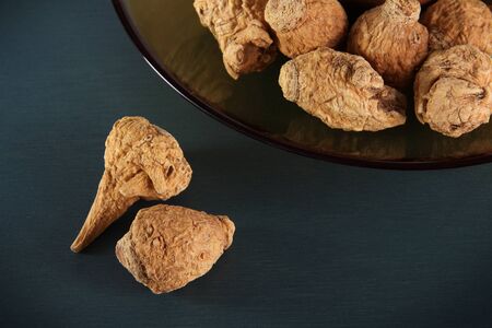 Dried maca root grains on blue green background.