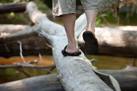 The man in bedroom-slippers walks on a logの写真素材